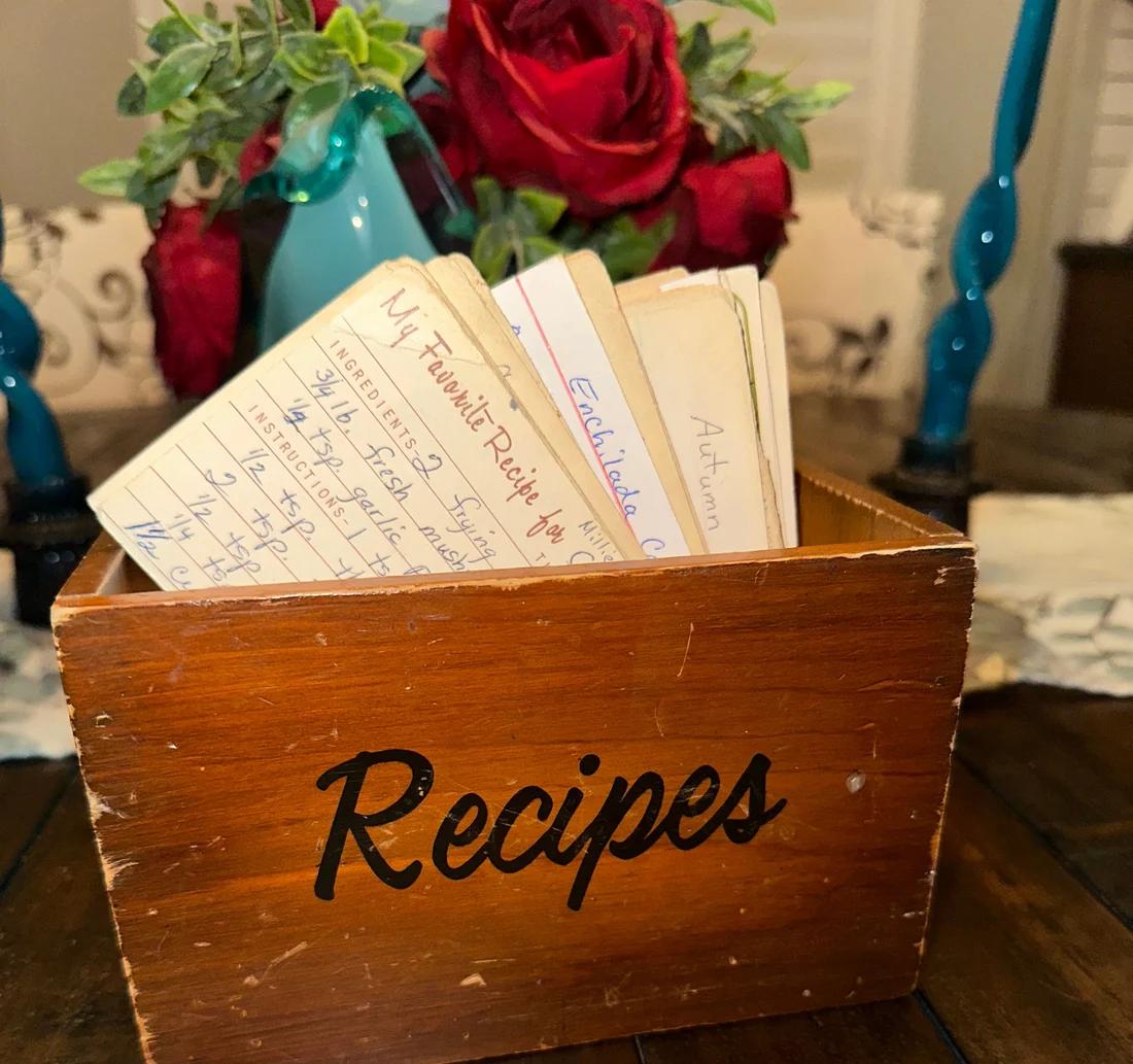 A worn wooden recipe box full of handwritten family recipe cards